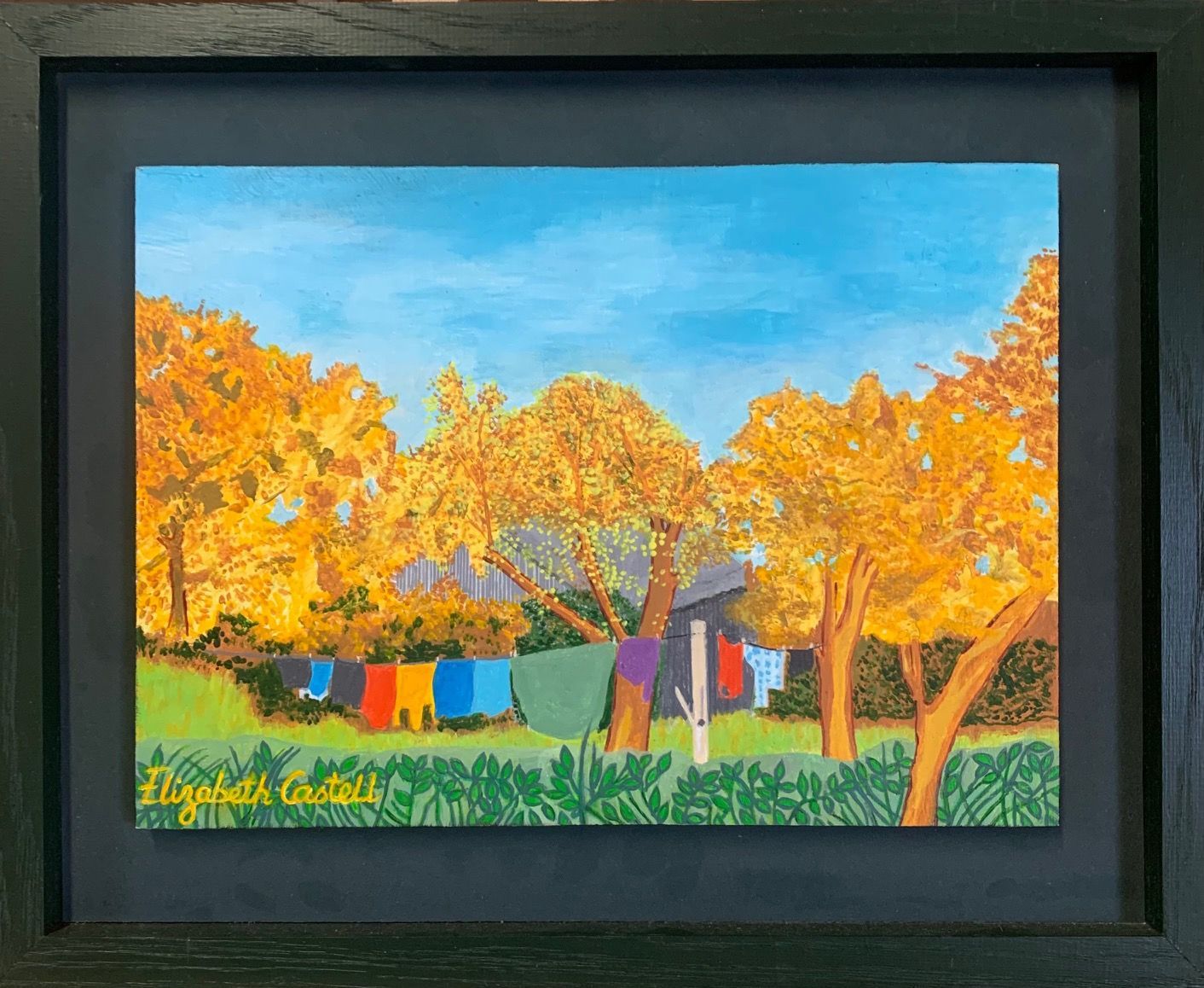 Painting of colorful laundry hanging outside under bright, golden trees and blue sky.