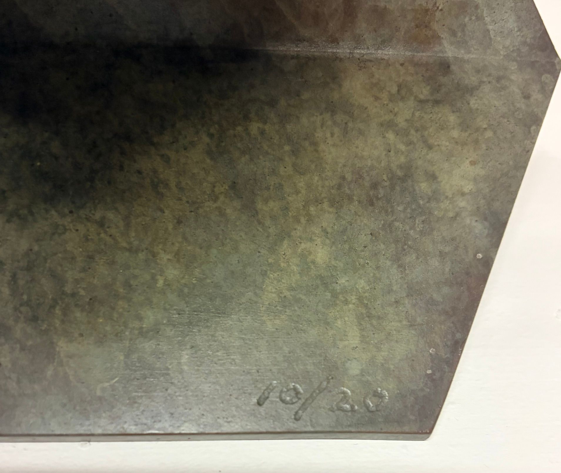 Close-up of a worn, dark metal surface with an embossed date stamp in the corner.