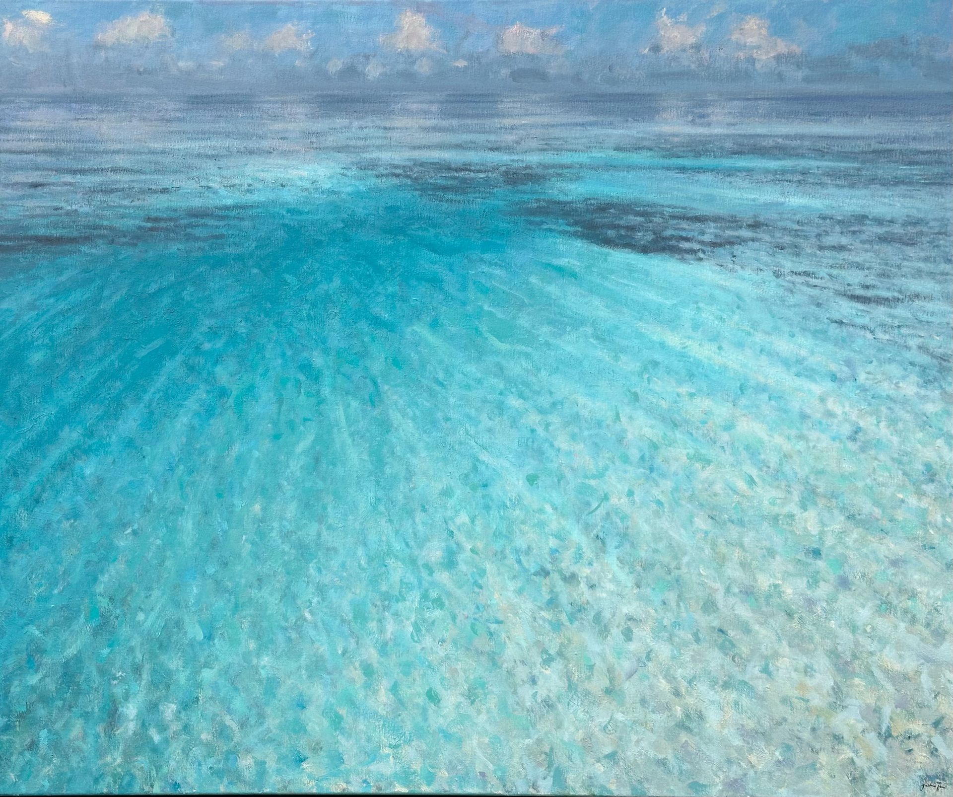 Turquoise ocean water fading to the horizon under a partly cloudy sky