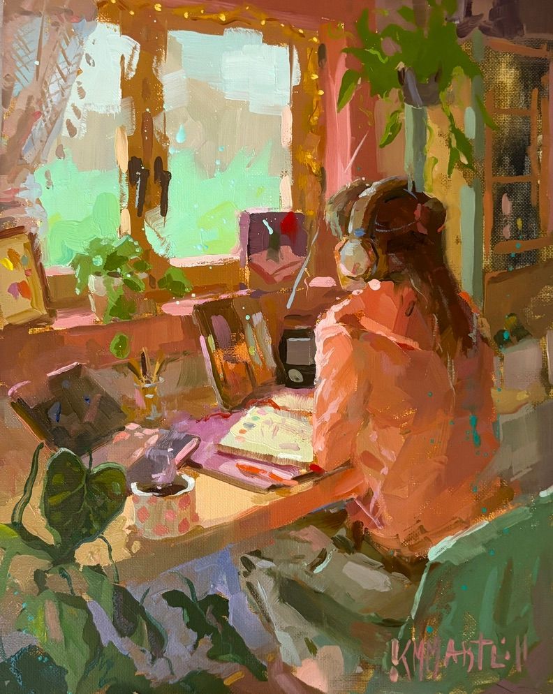 Woman sitting at a desk by a window, working on a tablet, surrounded by plants. Pink-toned room with warm sunlight.