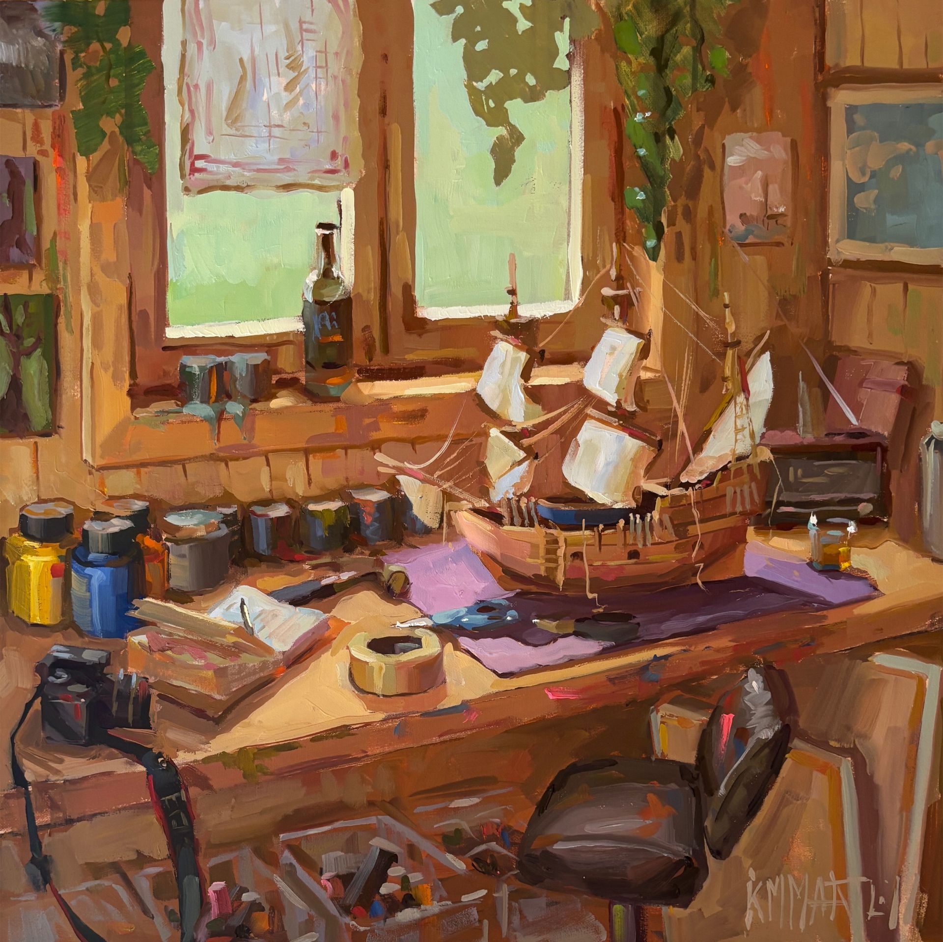 A sunlit studio with a wooden desk, sailboat model, and jars of paint.
