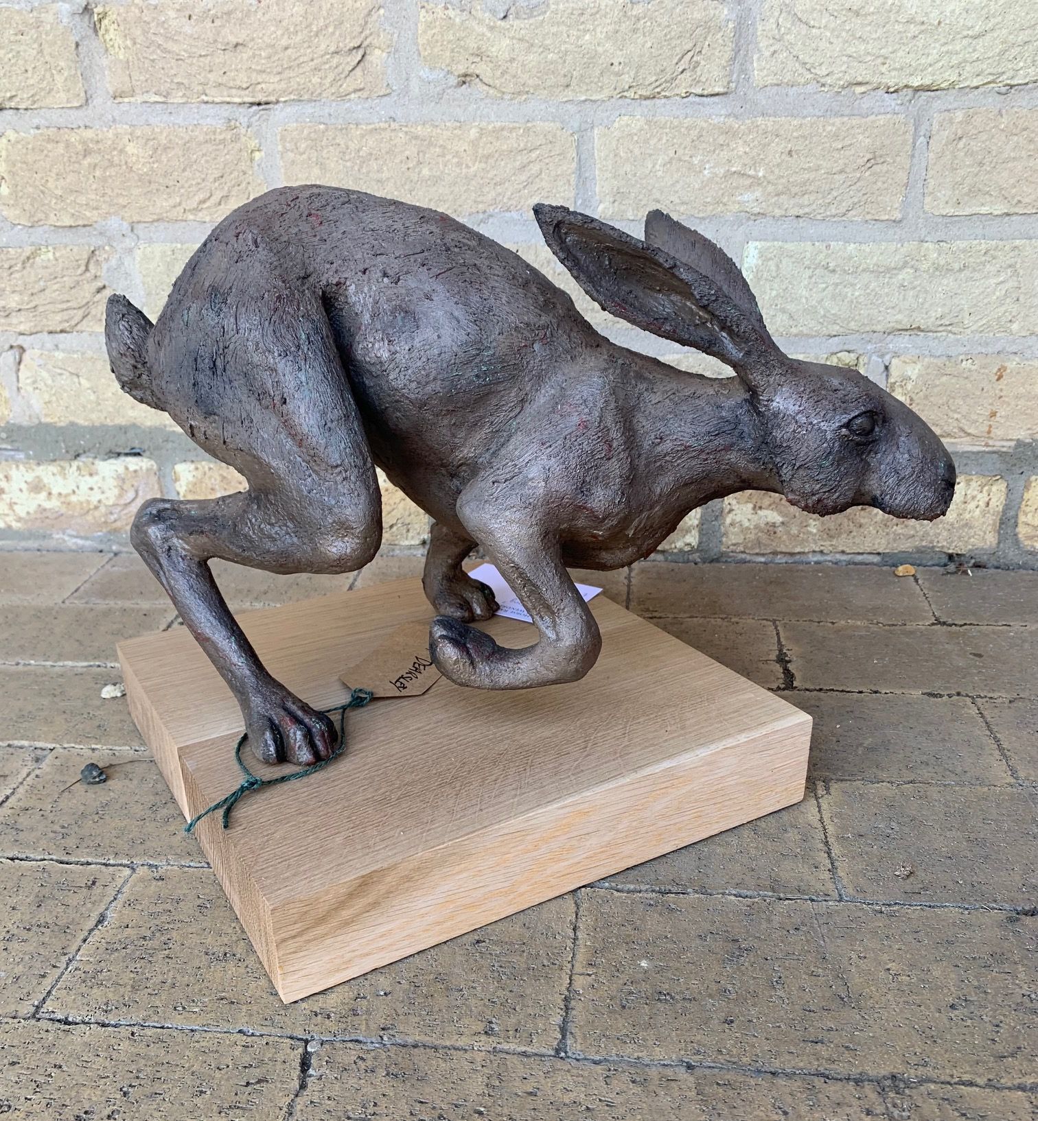 a statue of a running rabbit on a wooden base