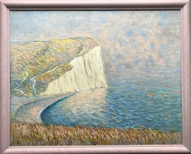 a framed painting of a cliff overlooking the ocean