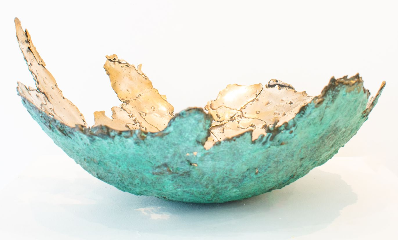 Bronze bowl with jagged beige edges on a white background