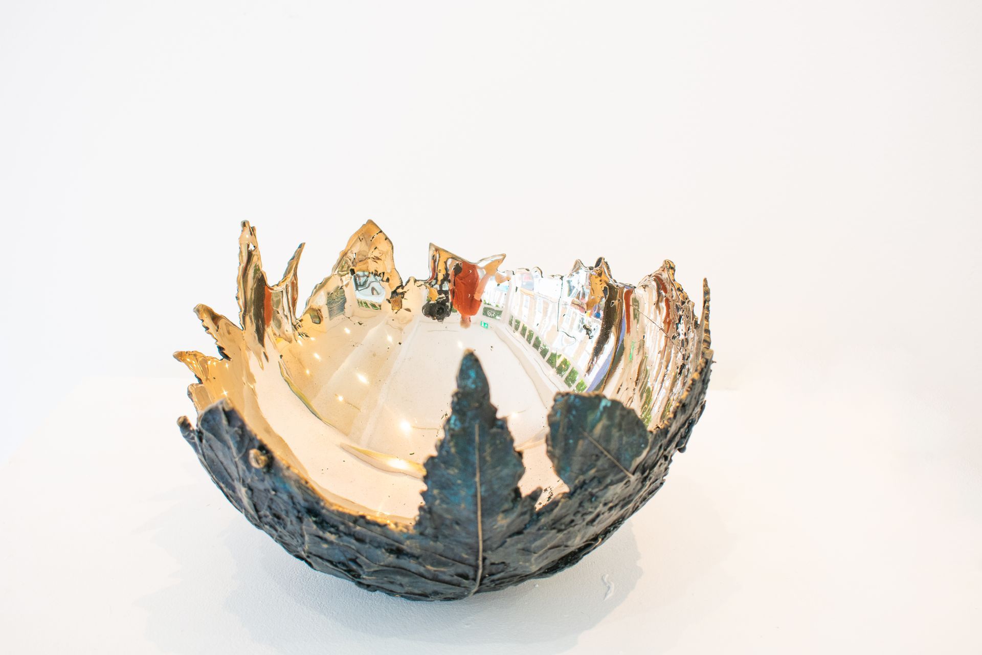 Metallic bowl with jagged silver and gold leaf-like edges on a white background