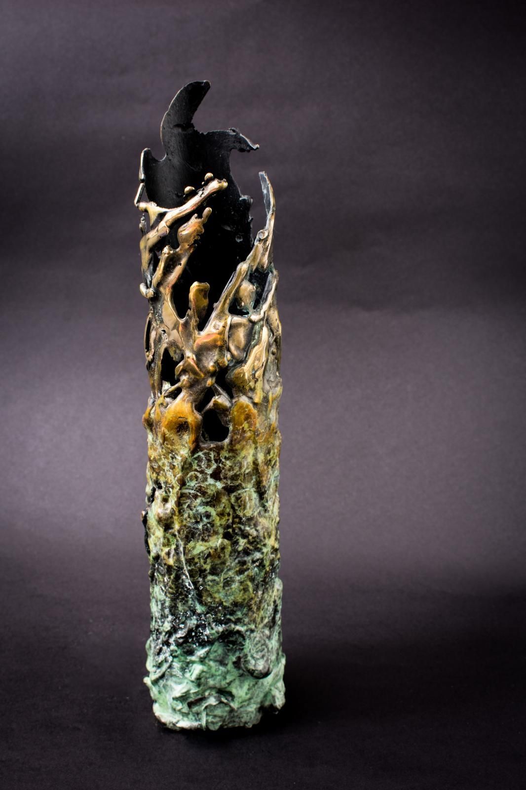 Abstract ceramic sculpture with black, gold, and green textures on a dark background