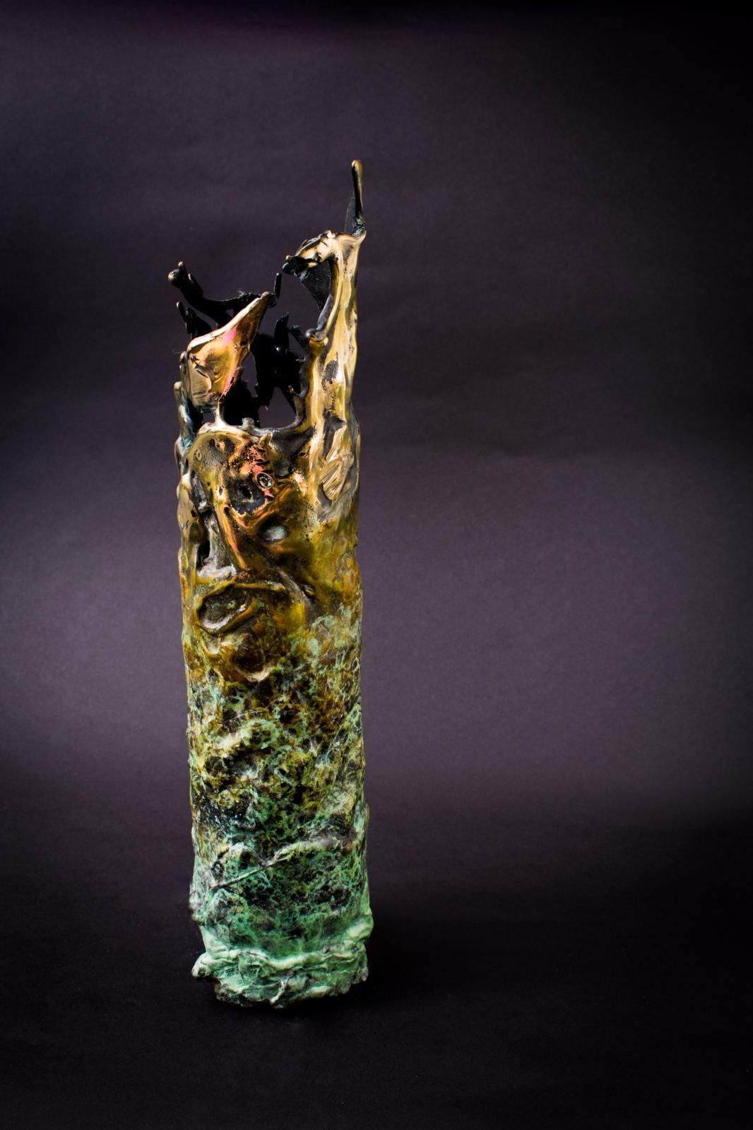 Abstract ceramic sculpture with black, gold, and green textures on a dark background