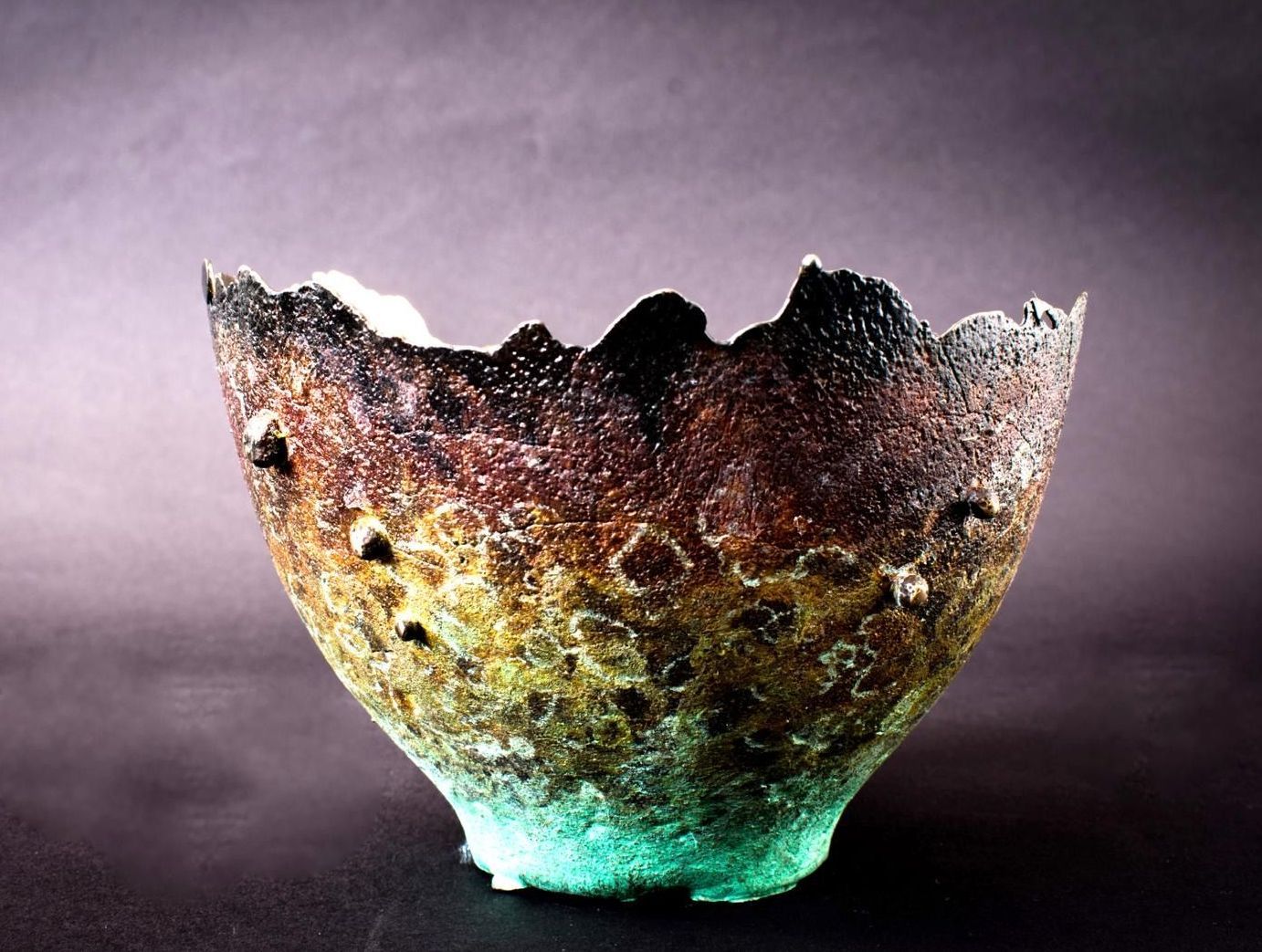 A brown and green bowl is sitting on a table