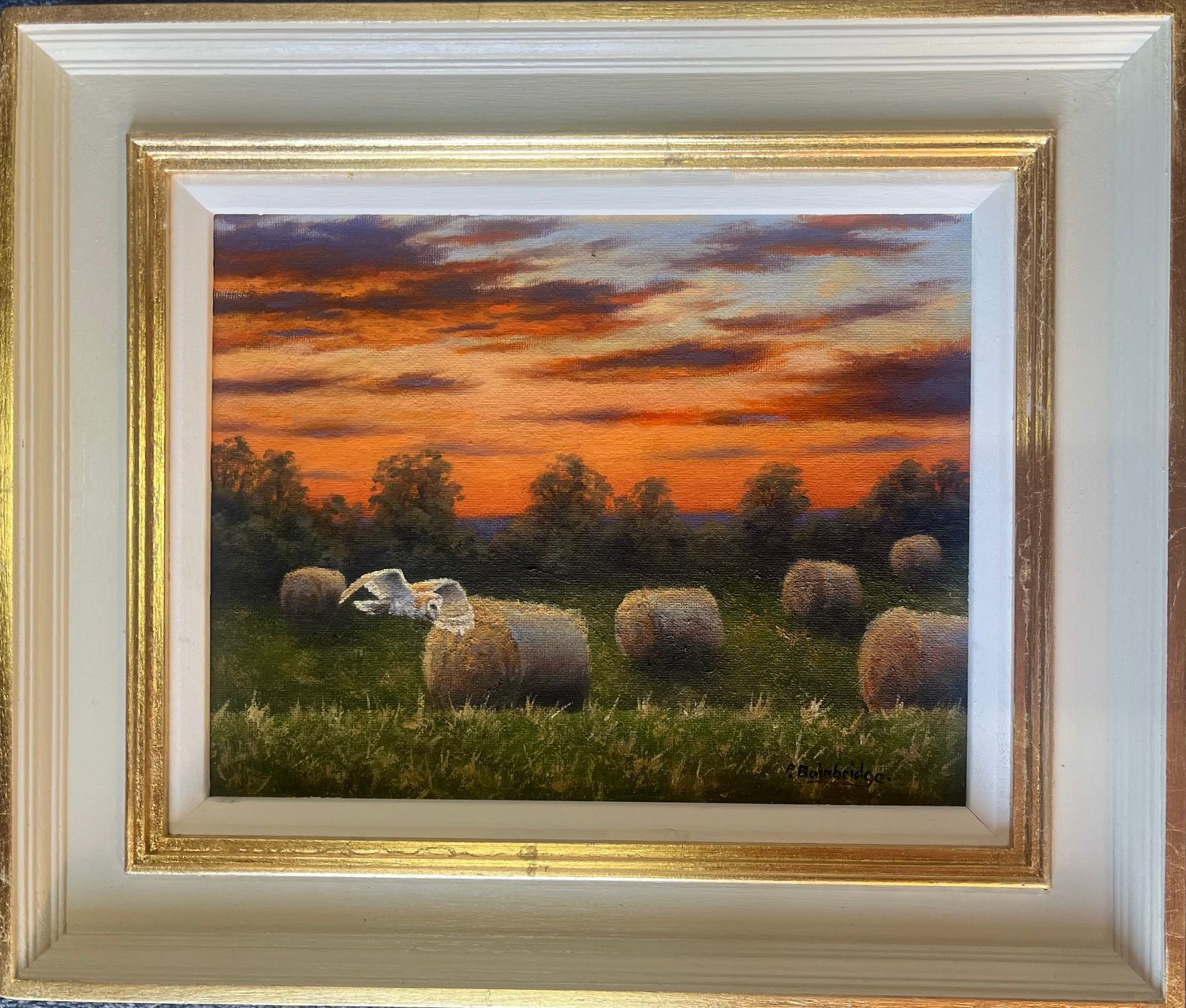 Hay bales in a field at sunset under an orange and purple sky