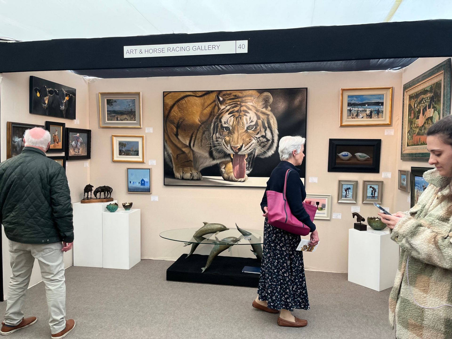 Art gallery booth with a large tiger painting and smaller framed artworks on display стенds
