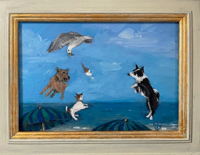 Dogs on a beach jumping at a seagull. Blue sky, umbrellas, and ocean waves.