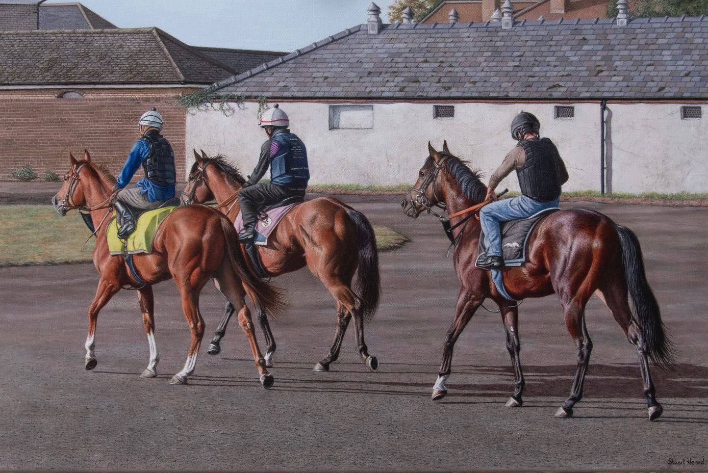 Three horses and riders on a track; a stable in the background. Riders wear helmets and jackets; horses are chestnut brown.