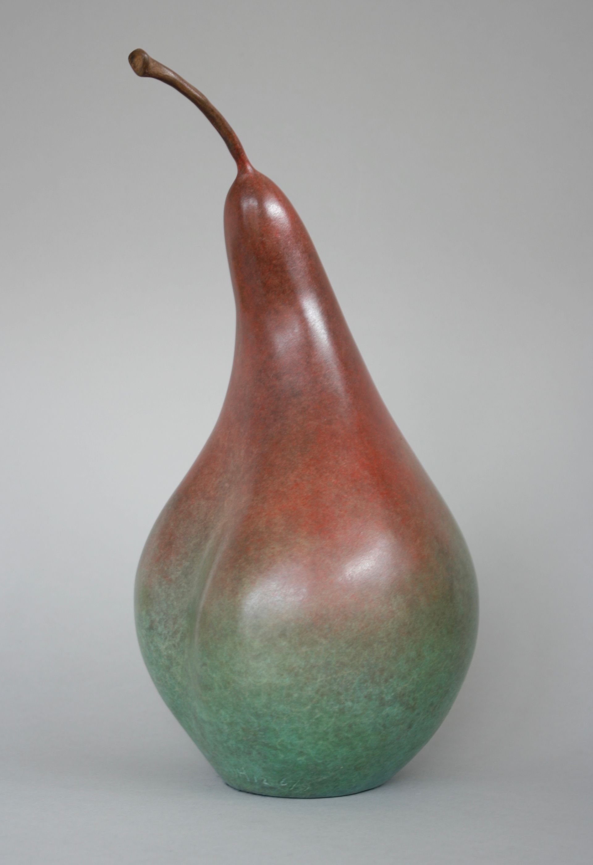 Bronze pear sculpture with red-brown top fading into green at the base.