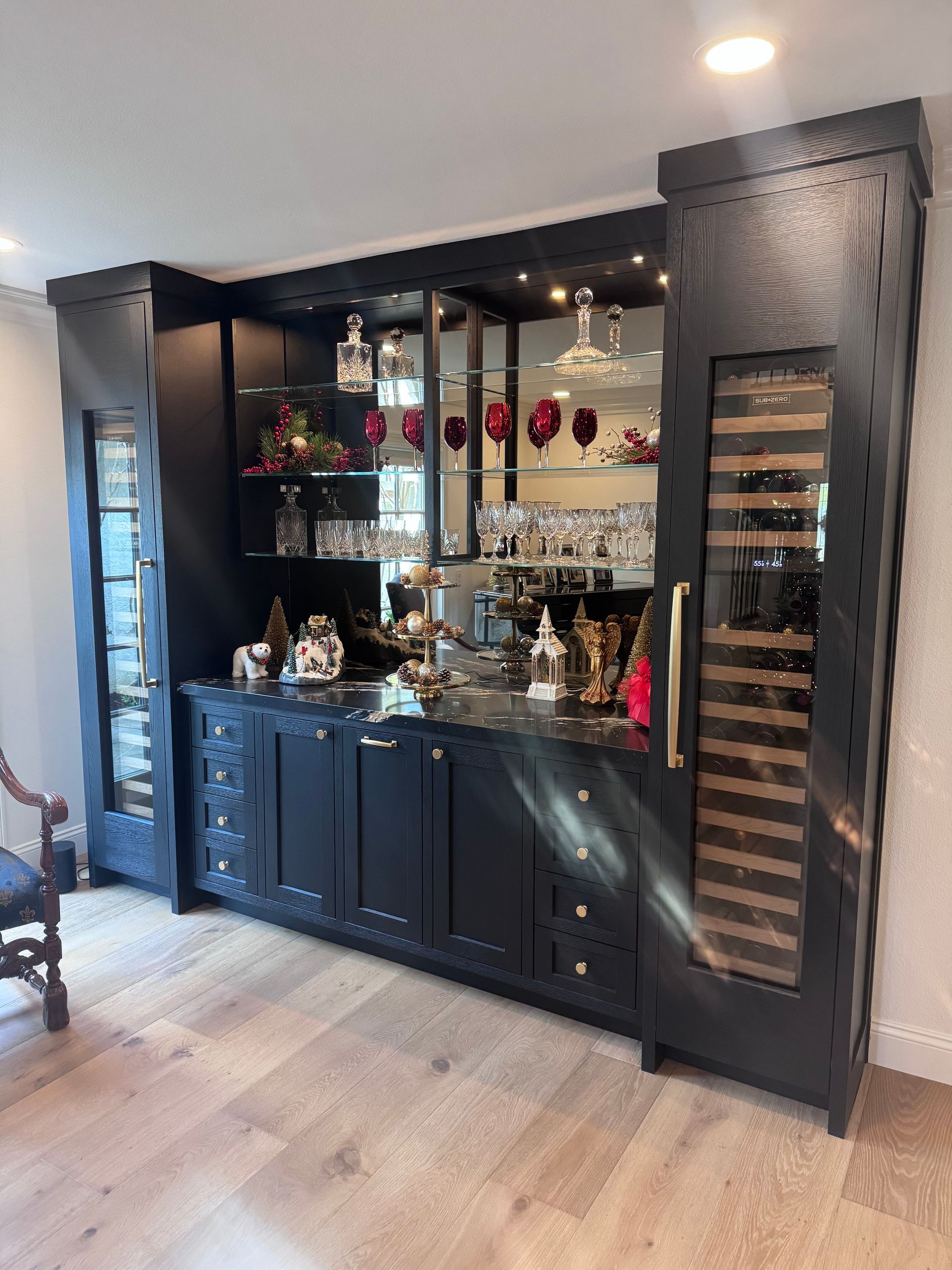Black bar cabinet with glassware, bottles, and decor in a modern room