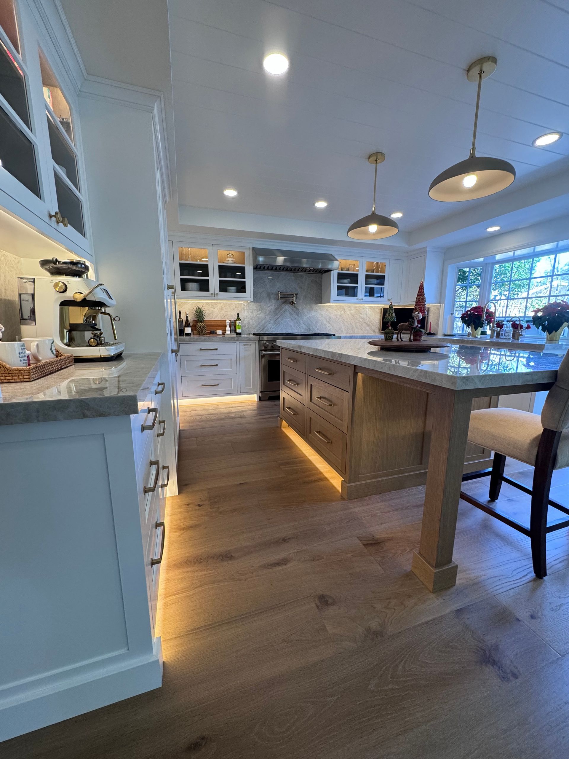 Bright modern kitchen with white cabinets, wood island, pendant lights, and hardwood floors