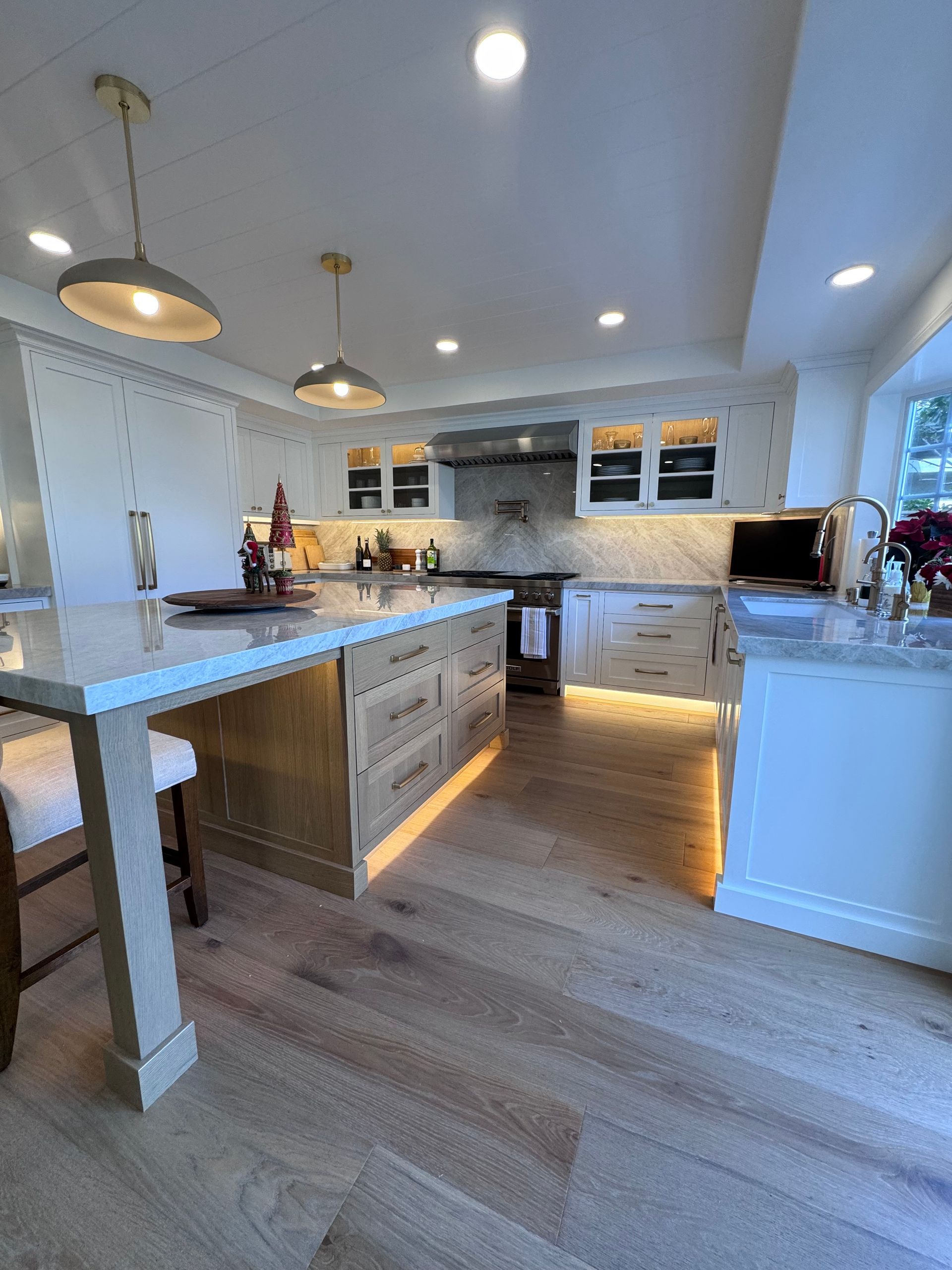 Bright modern kitchen with white cabinets, island seating, pendant lights, and hardwood floors