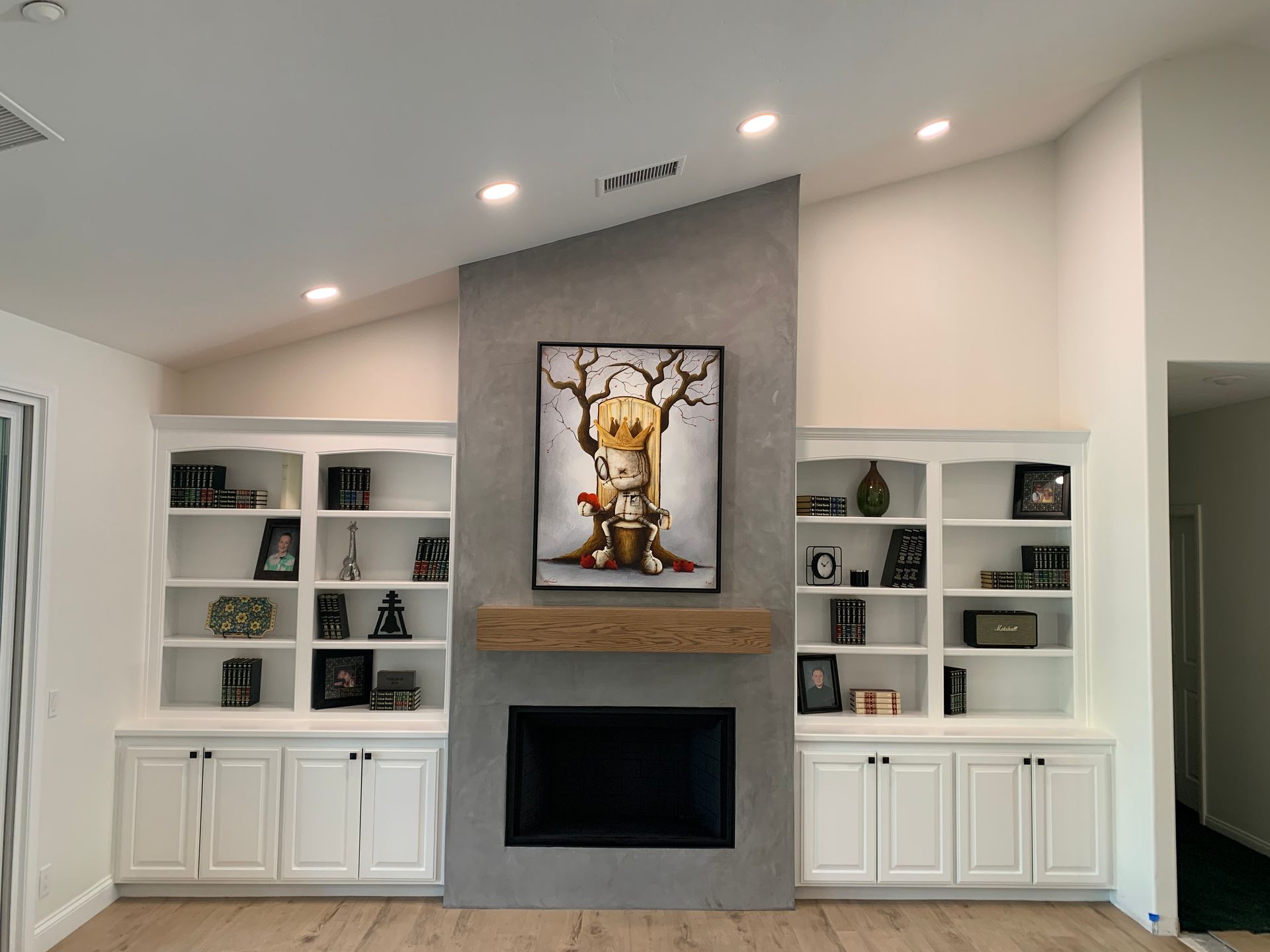 Modern living room fireplace wall with built-in white cabinets, shelves, and framed artwork