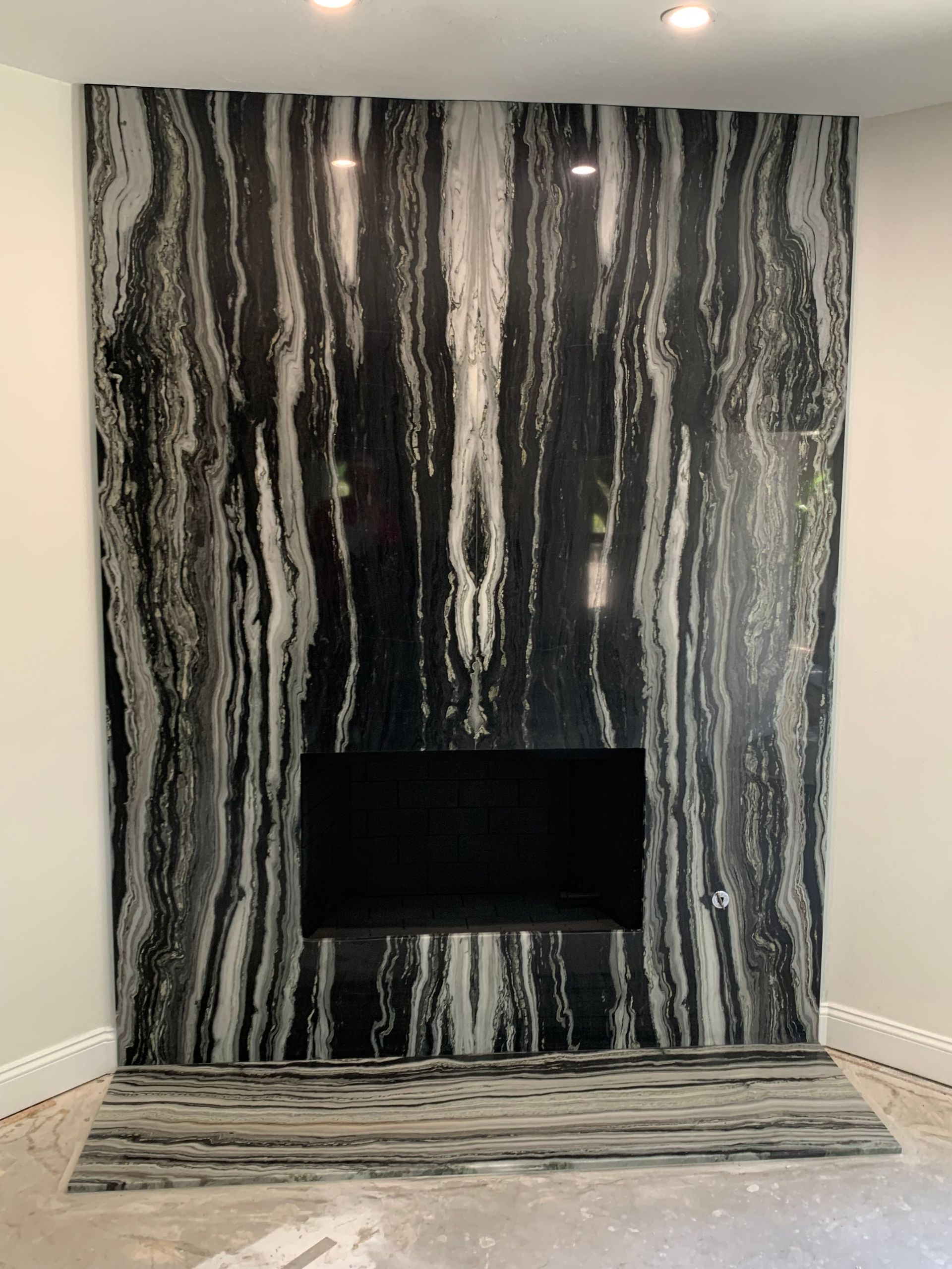 Black-and-white striped stone fireplace wall with a recessed firebox and matching hearth rug