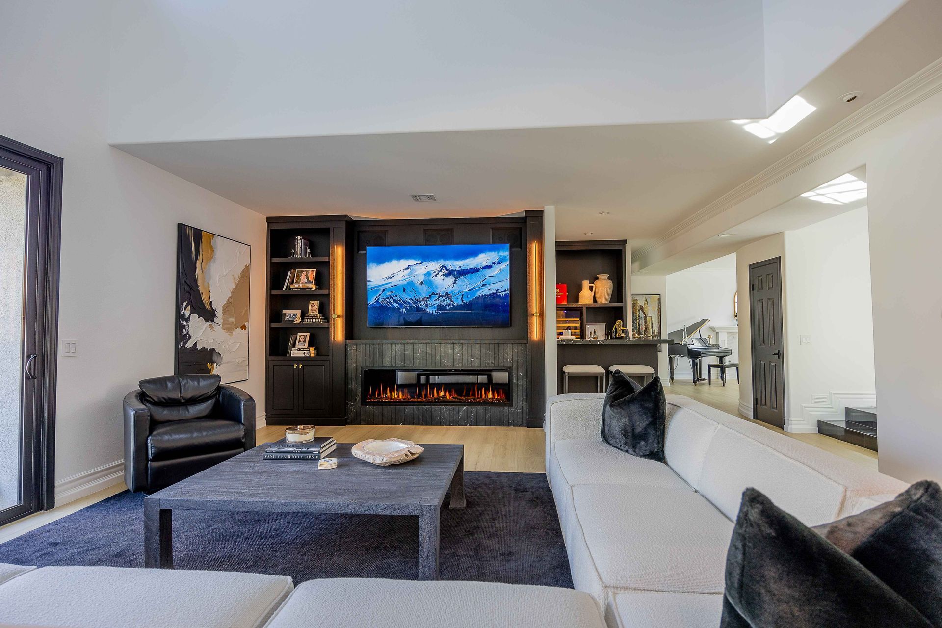 Modern living room with large TV, fireplace, gray sectional sofa, and dark area rug