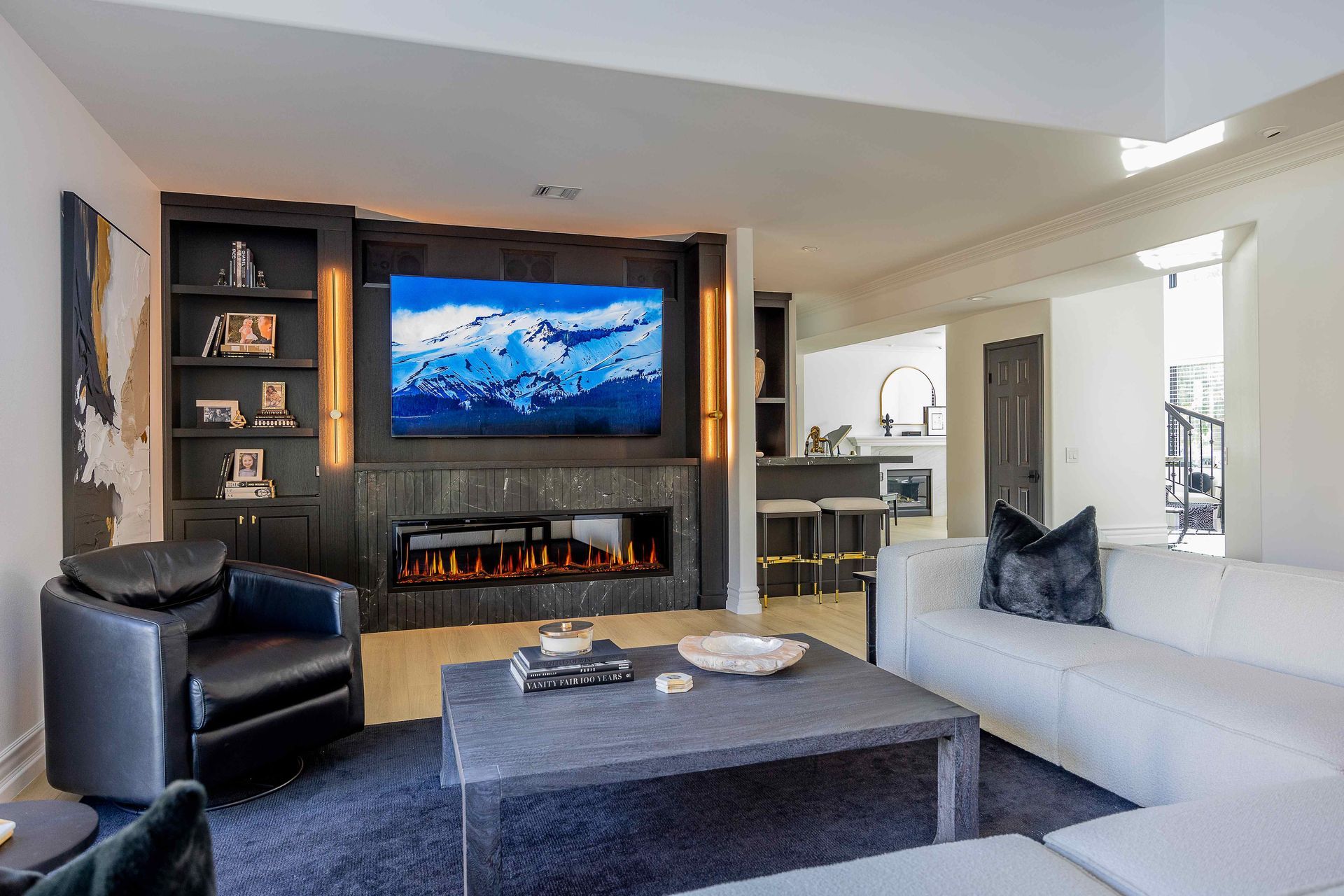 Modern living room with fireplace, mounted TV, gray sofa, black chair, and coffee table