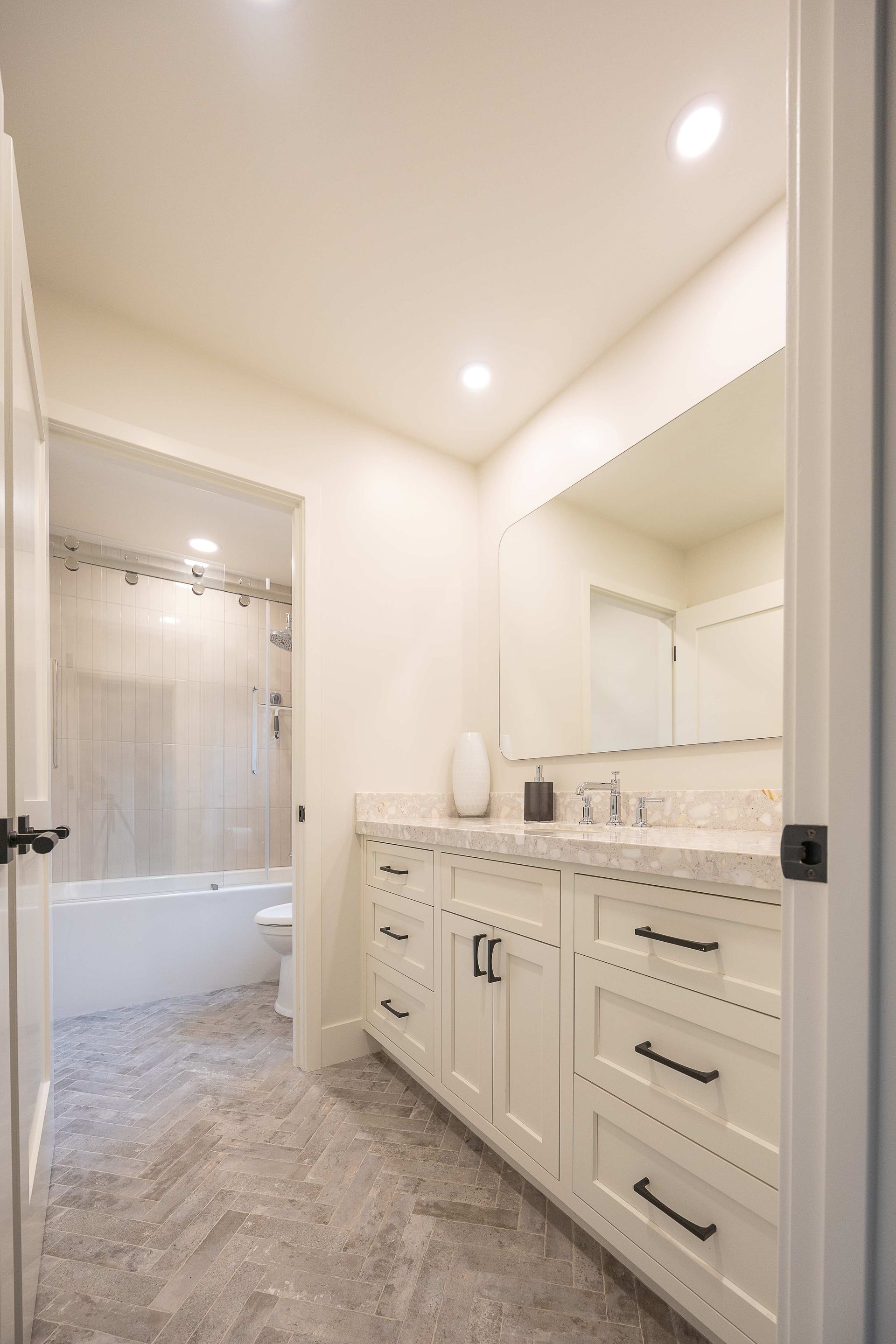 Bright bathroom with double vanity, large mirror, and bathtub in adjacent alcove