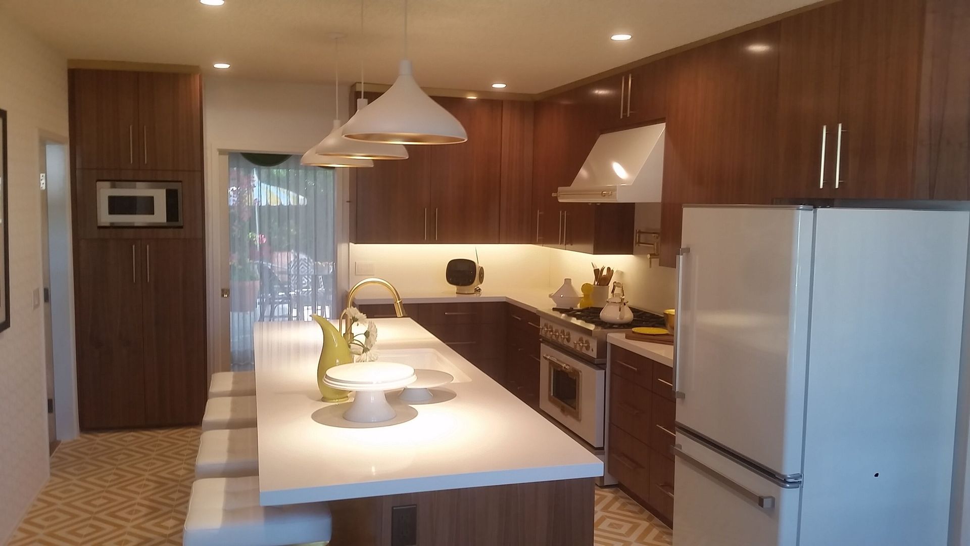 Modern kitchen with wood cabinets, white island, pendant lights, and stainless appliances