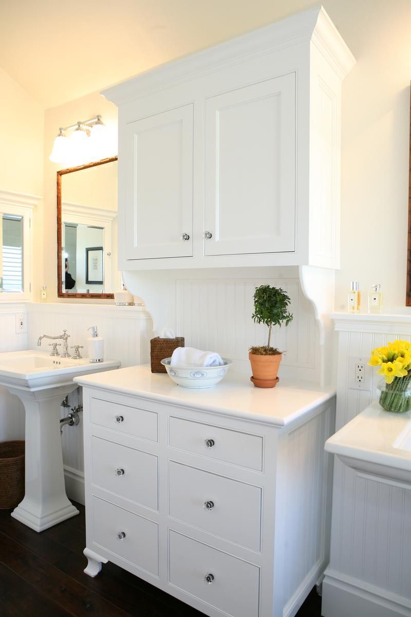 Bright white bathroom with vanity, sink, mirror, and potted plants