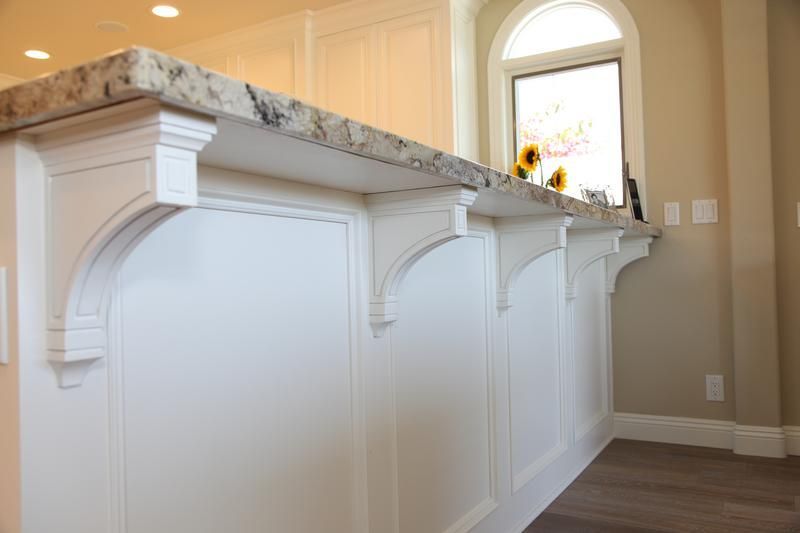 White paneled kitchen island with marble countertop in a bright room, near an arched window