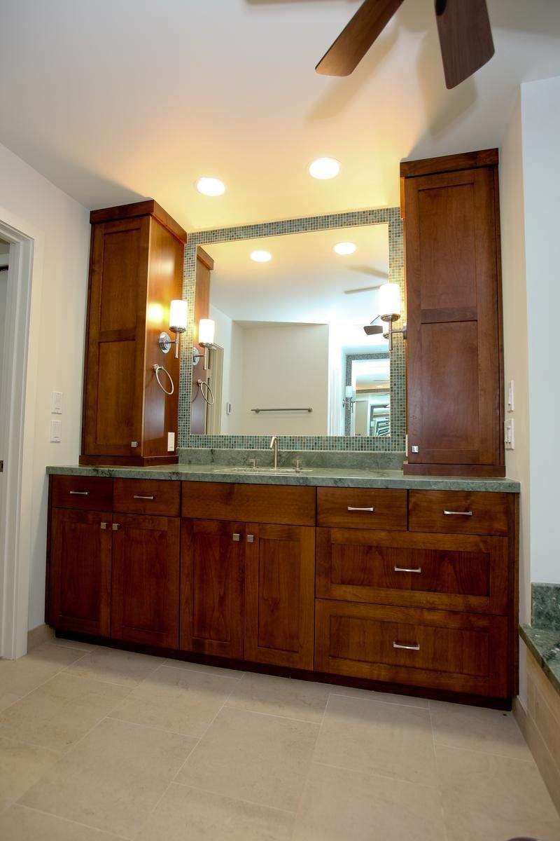 Wooden bathroom vanity with double sinks, large mirrored cabinet, and overhead lights