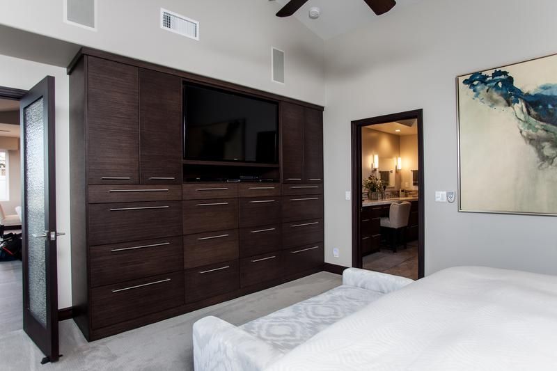 Modern bedroom with dark wood dresser, wall art, and a doorway to a bathroom