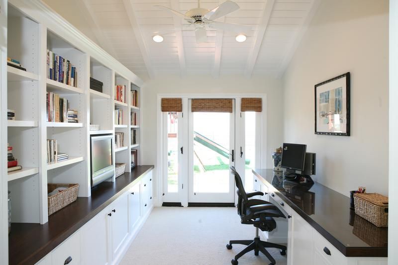 Bright home office with white built-in shelves, desk, computer, and glass doors to a patio.
