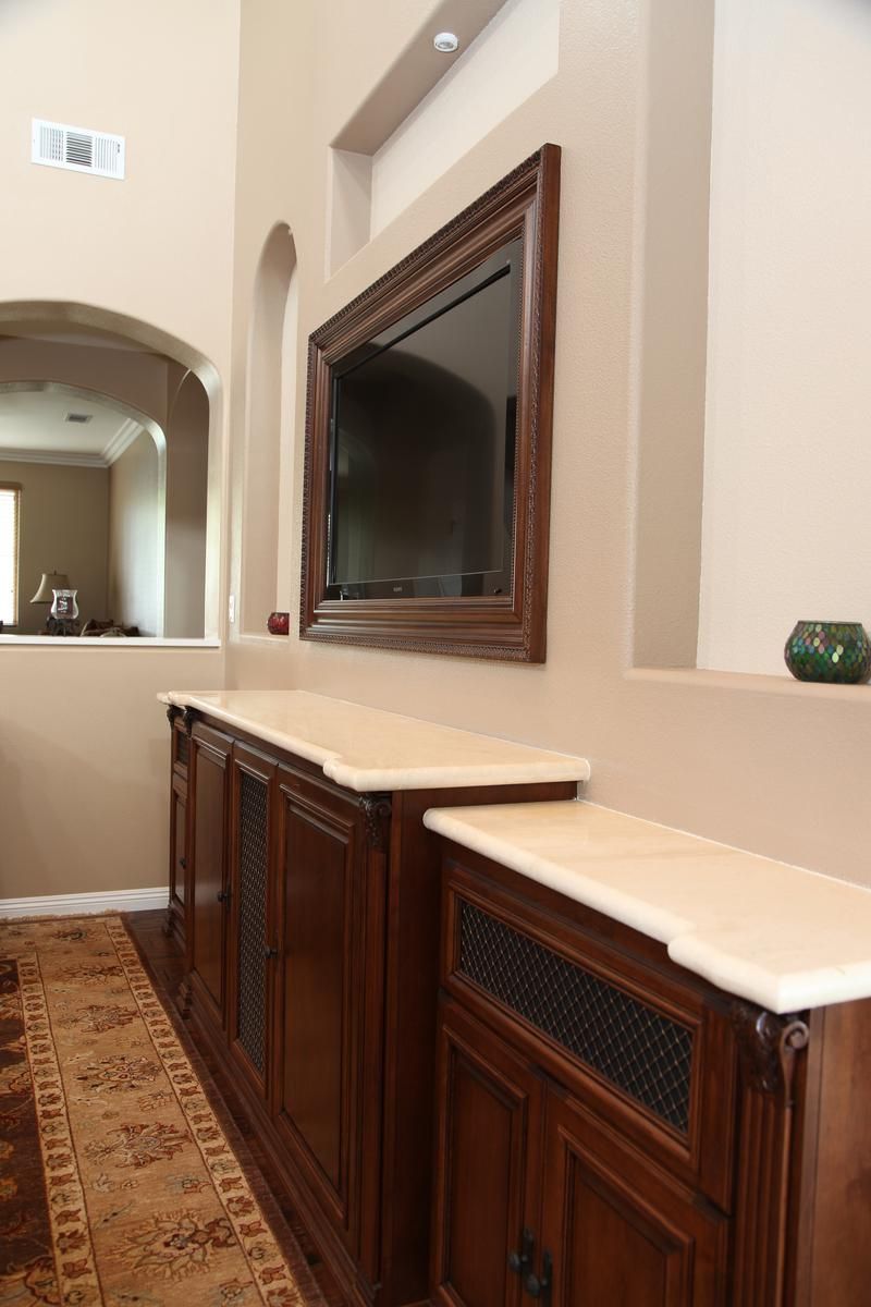 Hallway with dark wood cabinets and mirror along a beige wall over a patterned rug