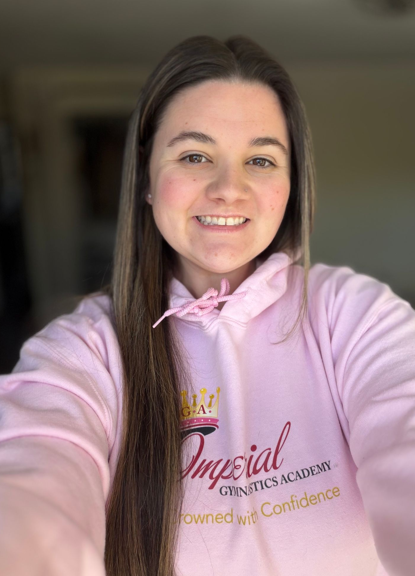 Woman with glasses and pink shirt, arms crossed, smiling.