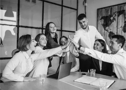 A group of people are giving each other a high five in a black and white photo.
