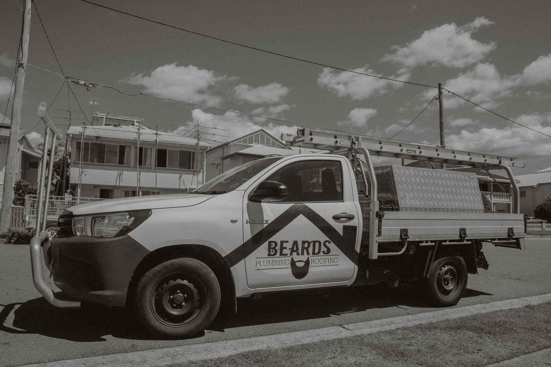 A Black and White Photo of a Truck Parked on the Side of the Road — Beards Roofing and Plumbing In Clontarf, QLD