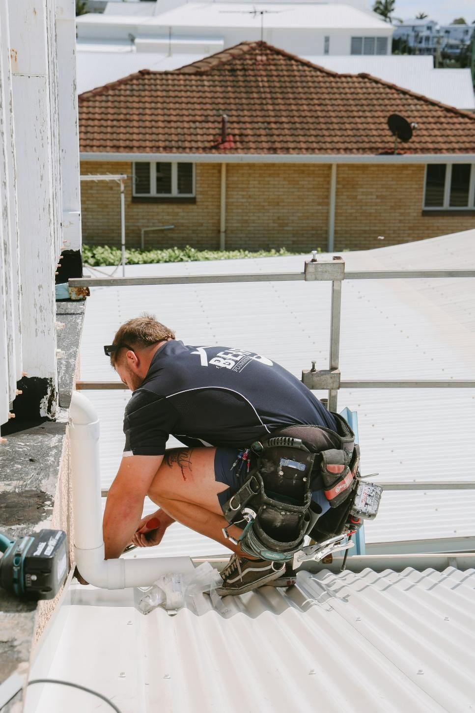 Man is Kneeling on a Roof Working on a Pipe — Beards Roofing and Plumbing in Clontarf, QLD