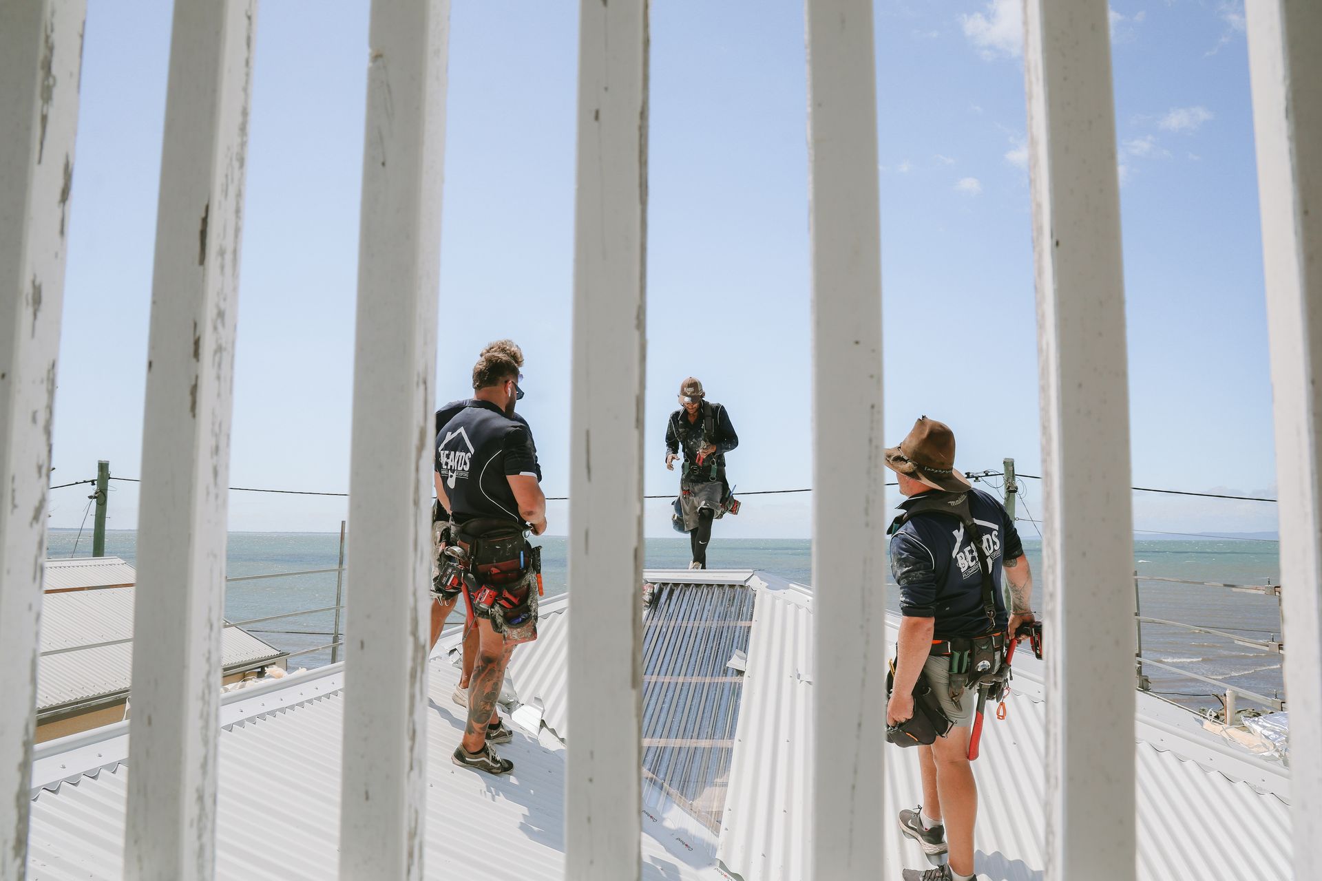 Four Men Are Standing on the Roof of a House — Beards Roofing and Plumbing in Brisbane, QLD