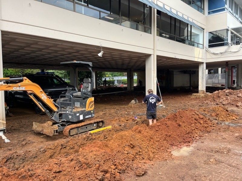 A Man is Digging in the Dirt in Front of a Building — Beards Roofing and Plumbing in Caboolture, QLD