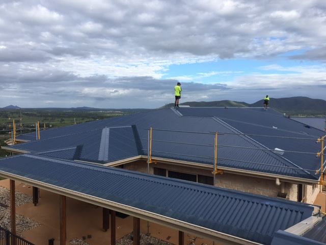 Two Men Are Standing on the Roof of a Building — Beards Roofing and Plumbing in North Lakes, QLD