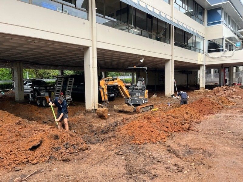 Man is Digging in the Dirt in Front of a Building — Beards Roofing and Plumbing in Clontarf, QLD