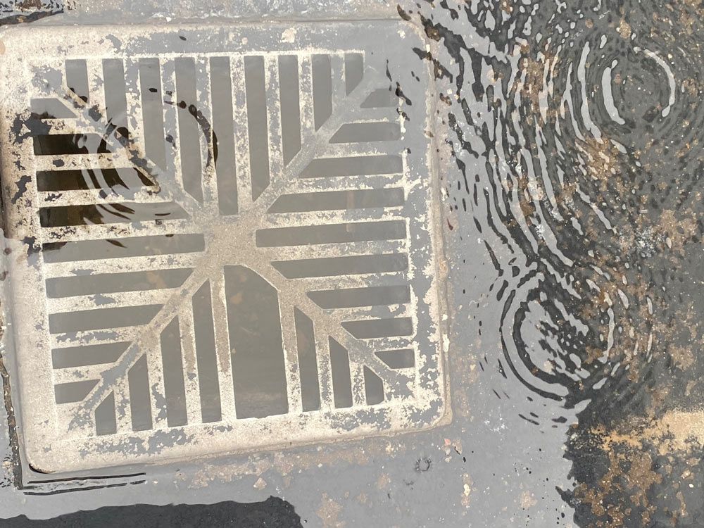 A Manhole Cover is Sitting in a Puddle of Water — Beards Roofing and Plumbing in Kallangur, QLD