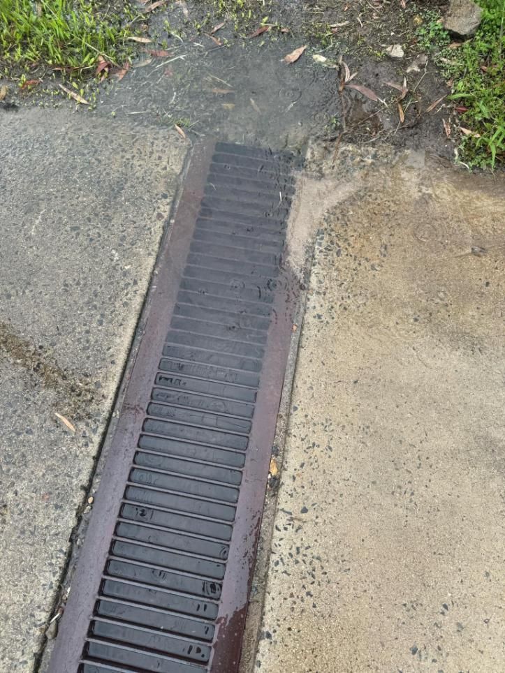 Close Up of a Drain on the Side of a Road — Beards Roofing and Plumbing in Clontarf, QLD