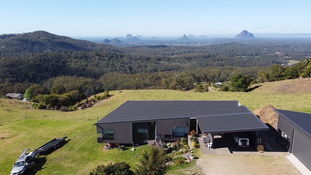 An Aerial View of a House on Top of a Hill With Mountains in the Background — Beards Roofing and Plumbing in Ipswich, QLD