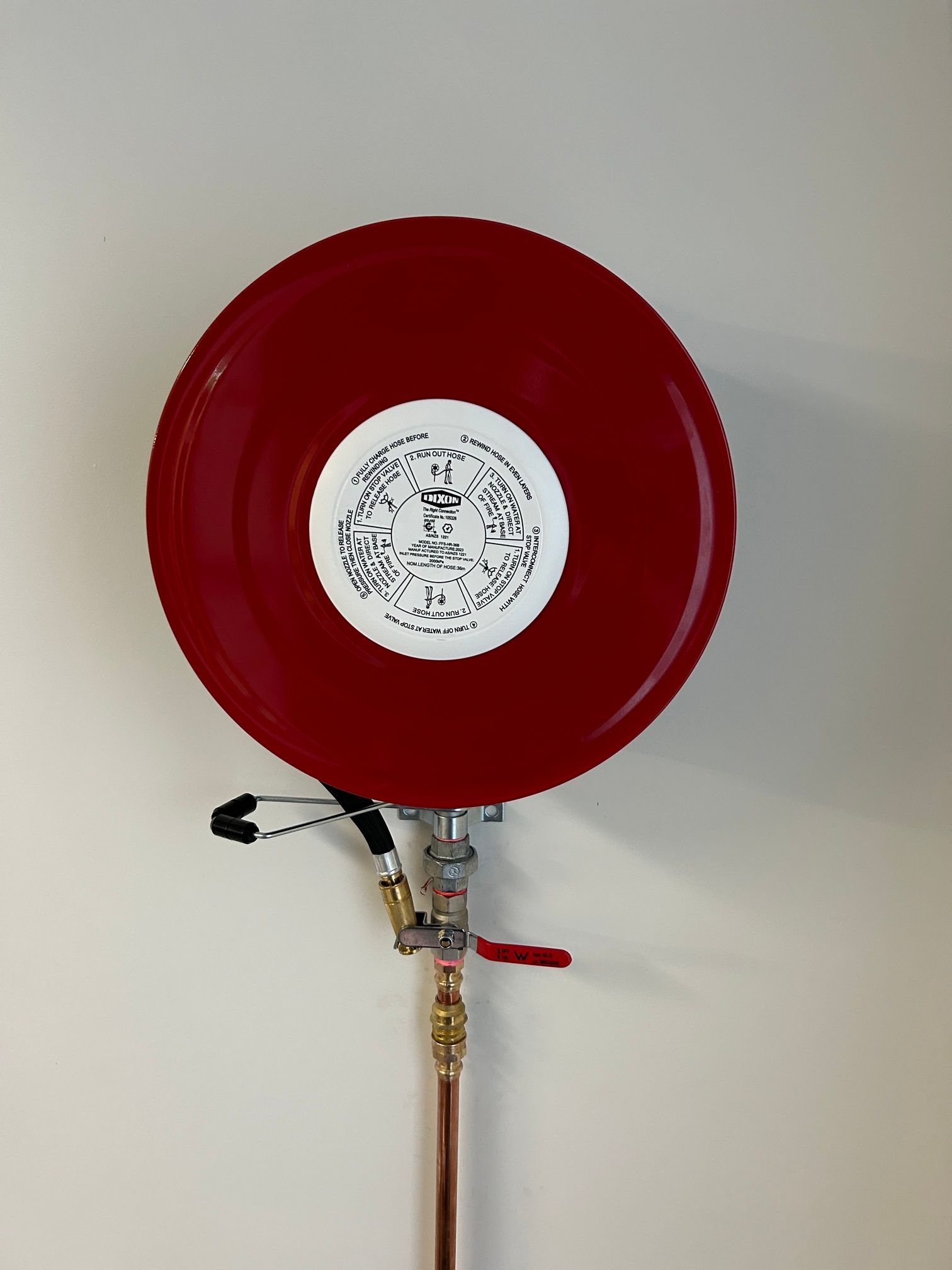 Red Fire Hose Reel With a White Label on It — Beards Roofing and Plumbing in Clontarf, QLD