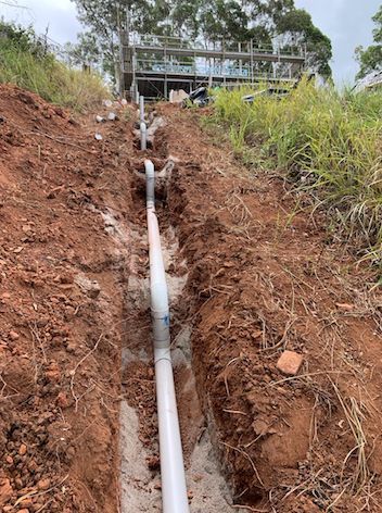 A Drain Pipe is Being Installed in the Dirt — Beards Roofing and Plumbing in Clontarf, QLD