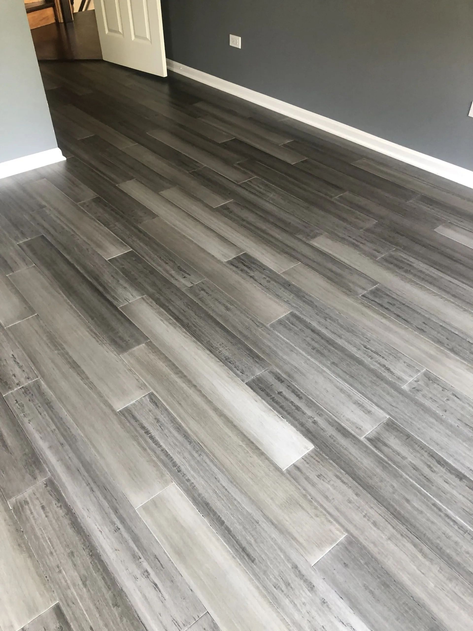 Empty room with gray wood-look flooring, dark gray walls, and a white door.
