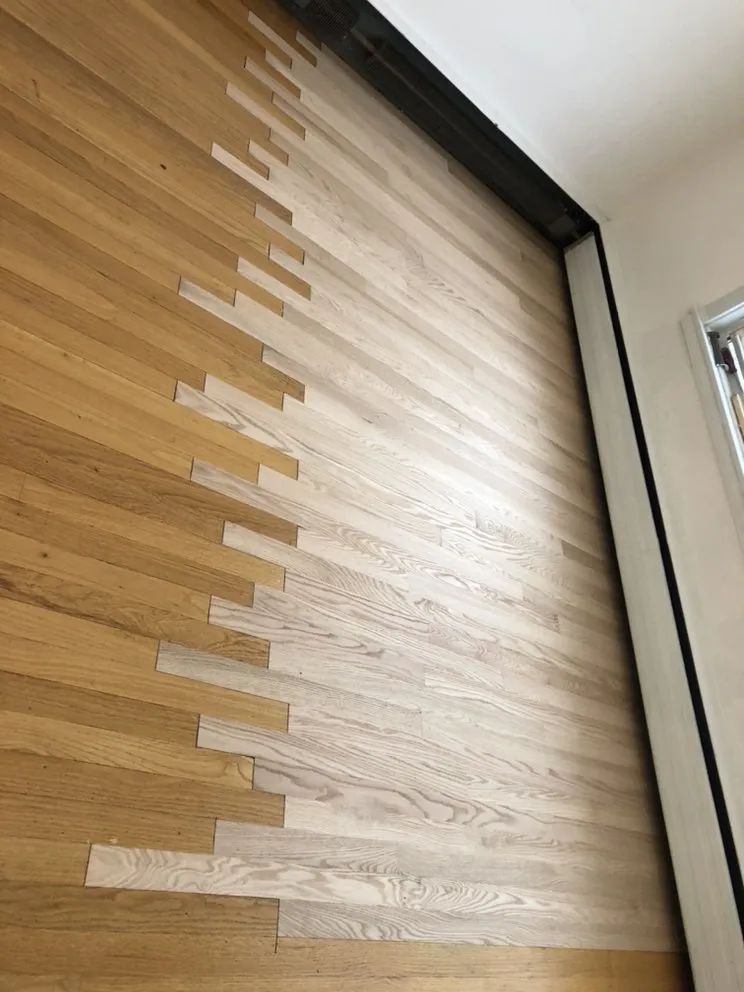 Wooden floor, half refinished. Light and dark wood sections meet with a jagged edge.
