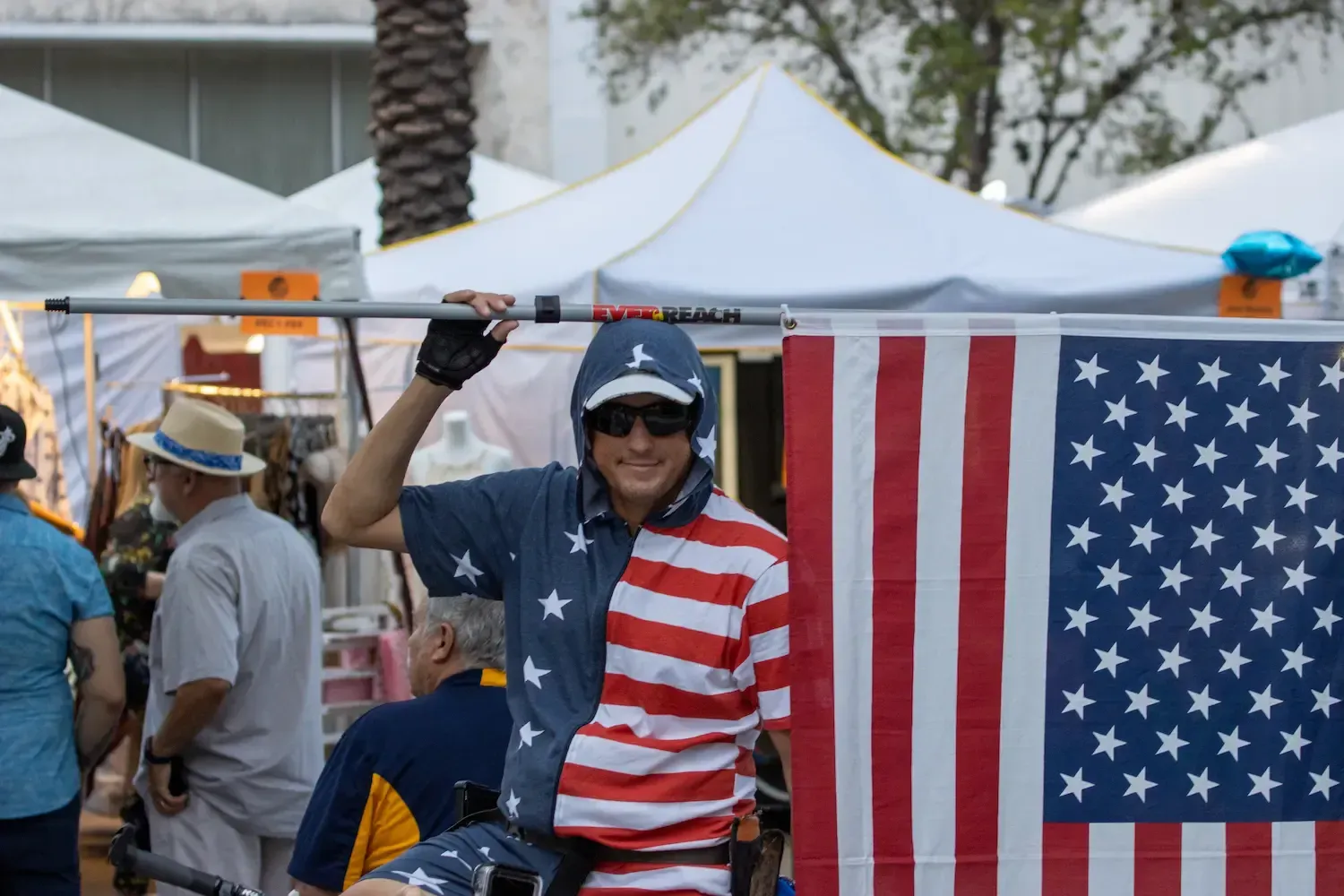 Man wearing a cap raises an American flag