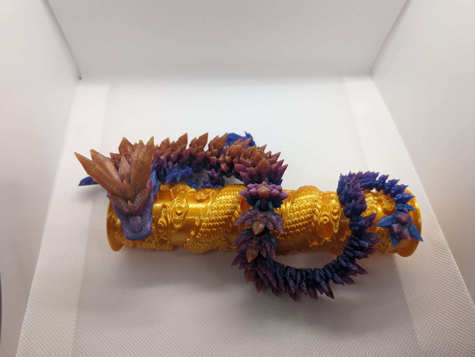 Colorful dragon-shaped figurine with gold, blue, and brown details in a white box.