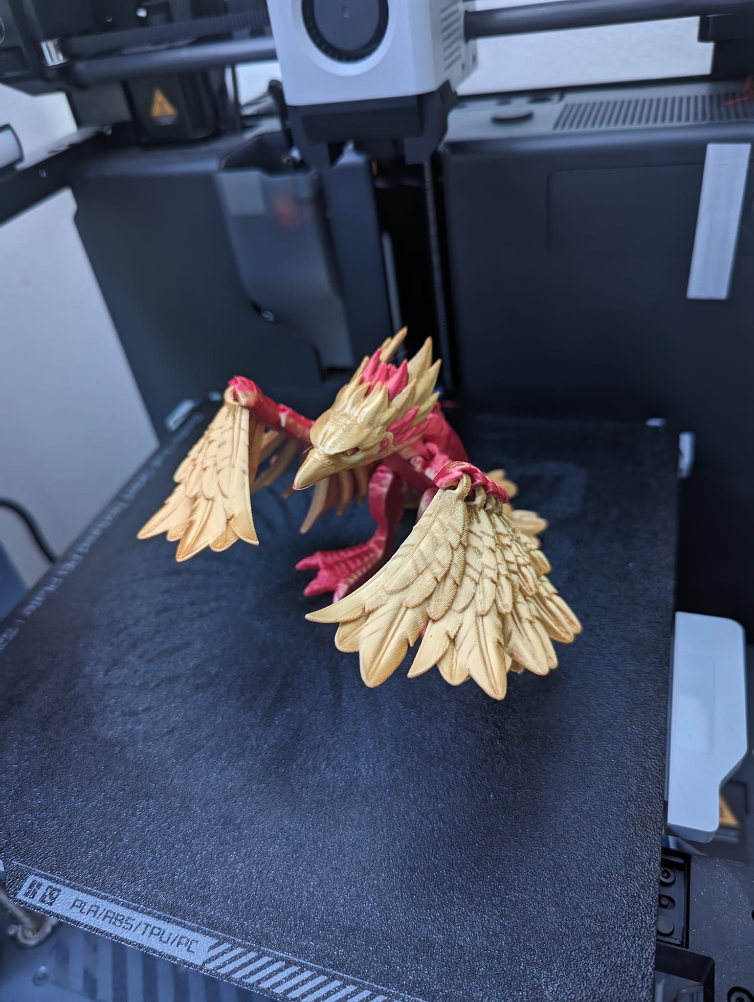 Gold-and-red dragon figurine on a 3D printer bed